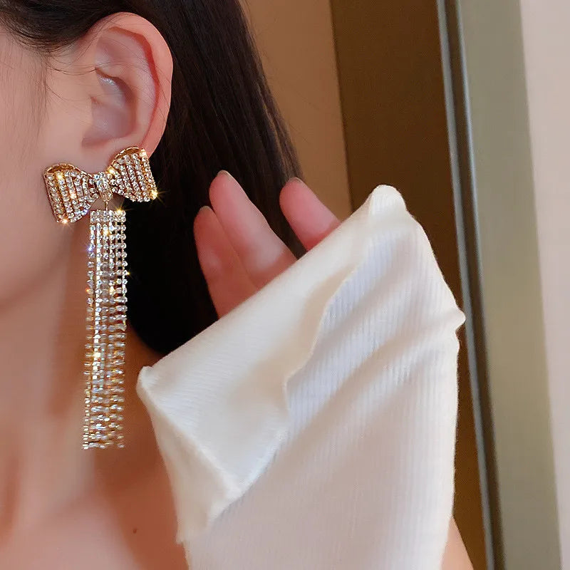 Selena - Boucles d'oreilles glamour avec nœud en cristal et pompon